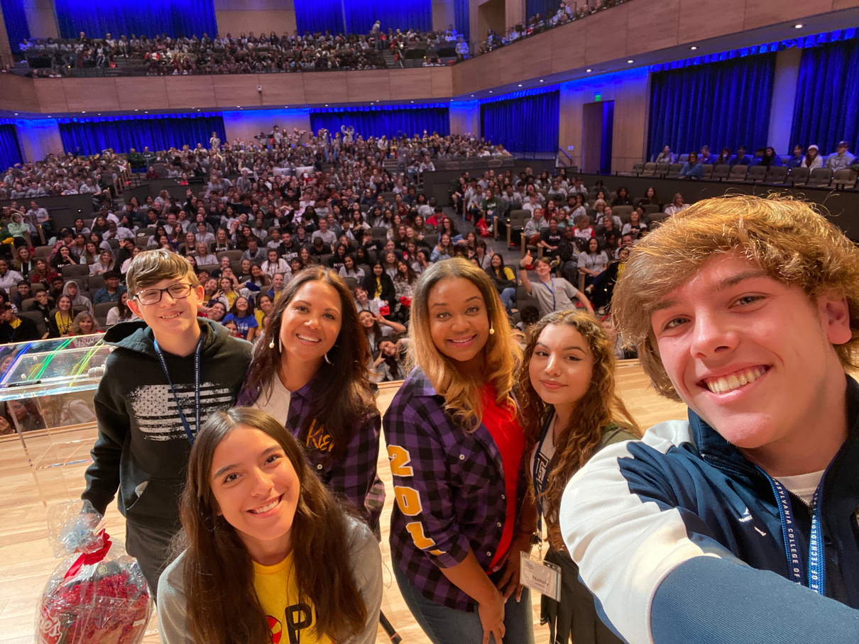 a group of people taking a selfie in front of an auditorium in Teen Conference